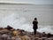 Teenager girl watching surfers in the ocean at cold and dark evening. Strandhill, Sligo, Ireland. Surfing in any nature conditions