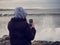 Teenager girl watching surfers in the ocean at cold and dark evening. Strandhill, Sligo, Ireland. Surfing in any nature conditions