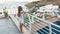 Teenager girl in white clothes standing on outdoor terrace at sea and swimming pool landscape. Tourist girl on resort