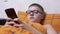 Teenager in Glasses Writing Text Messages on a Smartphone Lying in a Cozy Bed