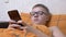 Teenager in Glasses Writing Text Messages on a Smartphone Lying in a Cozy Bed