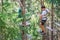 Teenager having fun on high ropes course, adventure park, climbing trees in a forest in summer