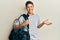 Teenager hispanic boy holding sport bag celebrating achievement with happy smile and winner expression with raised hand