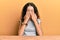 Teenager hispanic girl wearing casual clothes sitting on the table rubbing eyes for fatigue and headache, sleepy and tired