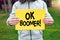 Teenager holds a banner with the word ok boomer against nature background