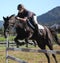 Teenager jumping black horse