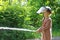 Teenager learning the firefighter profession. The girl in the fire helmet pours water from the hose