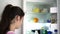 Teenager with long hair in ponytail opens large white fridge