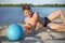 A teenager lying on the beach with a ball on a sunny day against the background of the river, a close-up