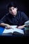 Teenager male doing homework by books with feather