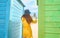 Teenager with a mask and glasses on the beach taking a selfie in the colorful huts. New normal concept