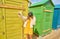 Teenager with a mask and glasses on the beach taking a selfie in the colorful huts. New normal concept