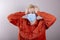 A teenager in a medical mask holds his head with his hands. Concept: headache, symptoms of coronavirus disease,