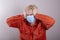 A teenager in a medical mask holds his head with his hands. Concept: headache, symptoms of coronavirus disease,