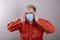 A teenager in a medical mask holds his head with his hands. Concept: headache, symptoms of coronavirus disease,