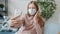 Teenager in medical mask posing for smartphone camera taking selfie indoors in apartment