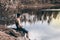 Teenager near the lake sits on a rock