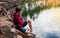 Teenager near the lake sits on a rock