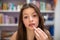 A teenager paints her lips and looks straight into the camera. Close-up view.