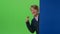 Teenager peeks out from behind a board shows the coin and the trumb up on a green screen