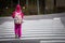 Teenager in a pink outfit with a cute backpack crossing the zebra on the street at daytime