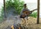 A teenager plays a guitar while sitting on the shore of a lake