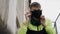 A teenager puts a black protective mask on his face while sitting on a metal ladder.