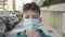 Teenager puts on a medical protective mask on a city street with car traffic and parking