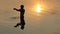 Teenager raises a handful of water in a lake at a sunset in slo-mo