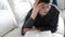 Teenager reading a book lying on the couch in room.