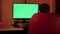 A teenager in a red chair in front of a green computer screen.