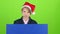 Teenager in a red hat appears from a board on a green screen. Slow motion