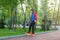 Teenager in red shirt spends free time training skating in the city park. Practicing skills freestyle, making tricks.