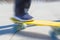 A teenager rides on a yellow pennyboard. Radial zoom blur action