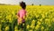 Teenager running with a water bottle in field of yellow flowers