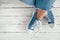 Teenager`s feet in casual blue new sneakers on the white wooden floor close up image. Vintage style in modern fashion world