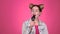 Teenager sings into the microphone. Pink background. Slow motion