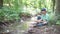 Teenager sits on the banks of a river in the forest