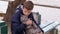 A Teenager Sits on a Bench with a Gray British Cat on Street, Holding the Leash.