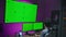 Teenager sits in front of PC and big screen with chroma key