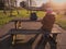 Teenager sitting on a bench in a park, her backpack on a wooden table, cold sunny day