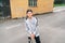 Teenager skateboarder boy in baseball cap street portrait holding skateboard on asphalt road near a grunge graffiti wall. Youth