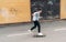 Teenager skateboarder boy riding on skateboard on asphalt road near a grunge graffiti wall. Youth generation Freetime spending