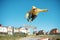 A teenager skateboarder does an flip trick in a skatepark on the outskirts of the city