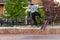 A teenager skateboarder is trying an ollie jump on the sidewalk. He loses his balance and falls off the skateboard.
