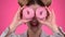 Teenager sniffs the cake and smile. Pink background. Close up