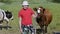 Teenager standing in pasture near with cows and holding glass of fresh milk. Healthy lifestyle