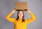 Teenager student girl taking cardboard box off her head having bright idea or plan.