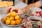 A teenager takes a wild apricots from a plate. Teacups with hot tea and with floral pattern, teapot, biscuits and plate with wild