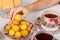 A teenager takes a wild apricots from a plate. Teacups with hot tea and with floral pattern, teapot, biscuits and plate with wild